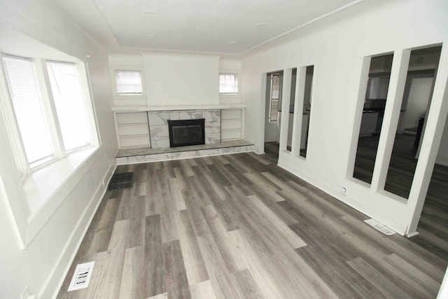 unfurnished living room featuring hardwood / wood-style flooring and a stone fireplace