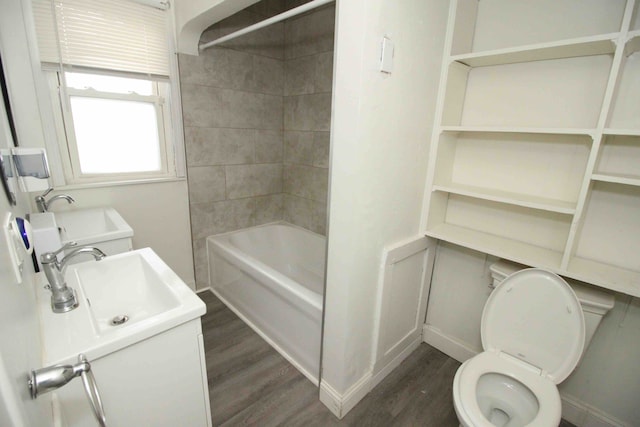 full bathroom featuring hardwood / wood-style floors, tiled shower / bath combo, toilet, and sink