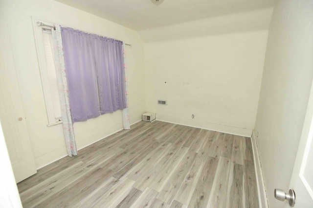 unfurnished room with light wood-type flooring and lofted ceiling