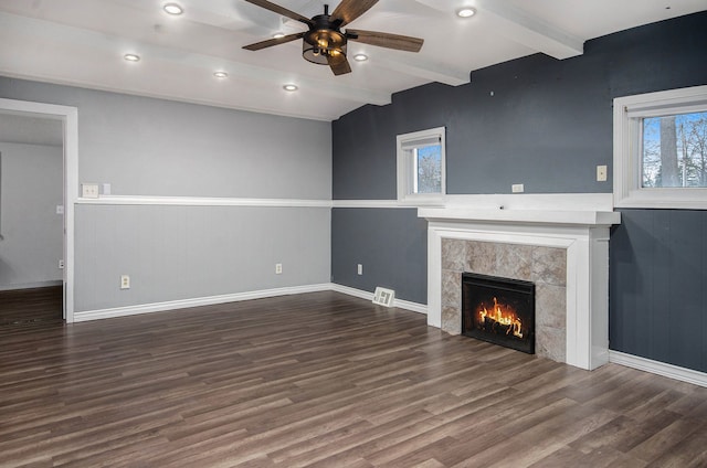 unfurnished living room featuring beamed ceiling, a fireplace, dark wood-type flooring, and ceiling fan