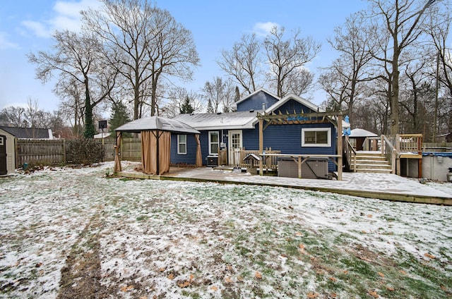 snow covered rear of property featuring a gazebo, a storage shed, a hot tub, and a deck