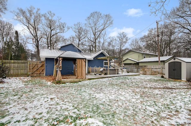 snow covered house featuring a storage shed, a wooden deck, and a hot tub