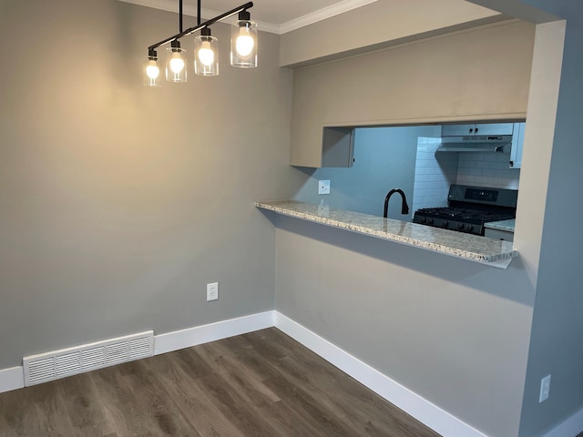 kitchen with gas stove, light stone countertops, hanging light fixtures, backsplash, and ornamental molding