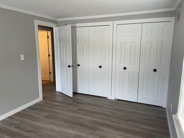 unfurnished bedroom with crown molding, dark wood-type flooring, and two closets
