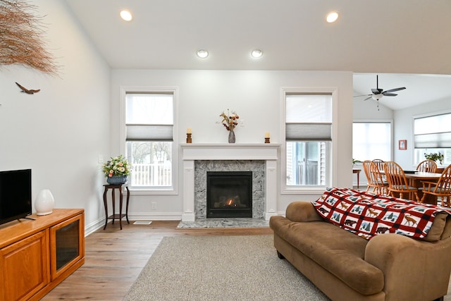 living room with ceiling fan, light hardwood / wood-style floors, plenty of natural light, and a premium fireplace