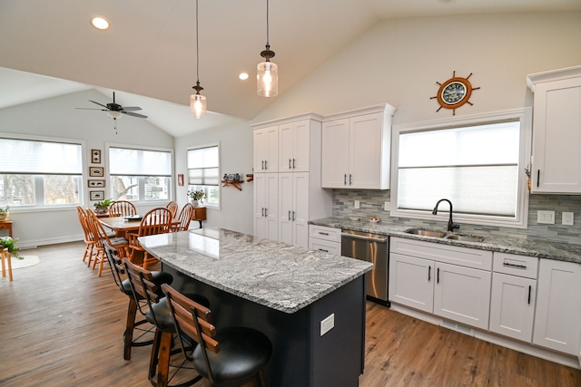 kitchen featuring tasteful backsplash, sink, dishwasher, a center island, and white cabinetry