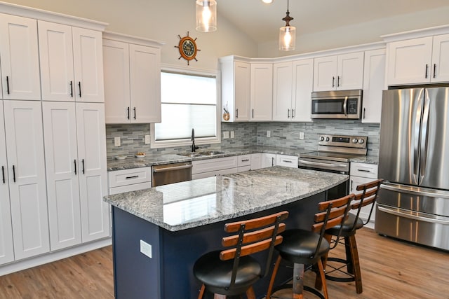 kitchen with a center island, stainless steel appliances, white cabinetry, and hanging light fixtures