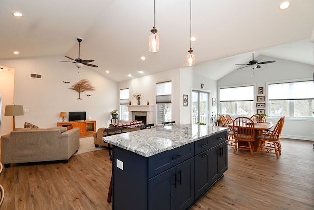 kitchen with dark hardwood / wood-style flooring, a center island, decorative light fixtures, and ceiling fan