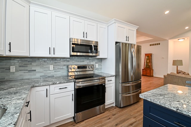 kitchen with white cabinets, appliances with stainless steel finishes, decorative backsplash, and light hardwood / wood-style flooring