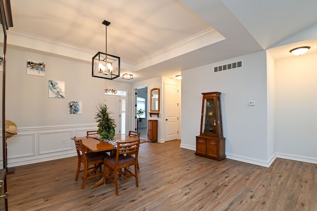 dining space with a notable chandelier, ornamental molding, dark wood-type flooring, and a tray ceiling