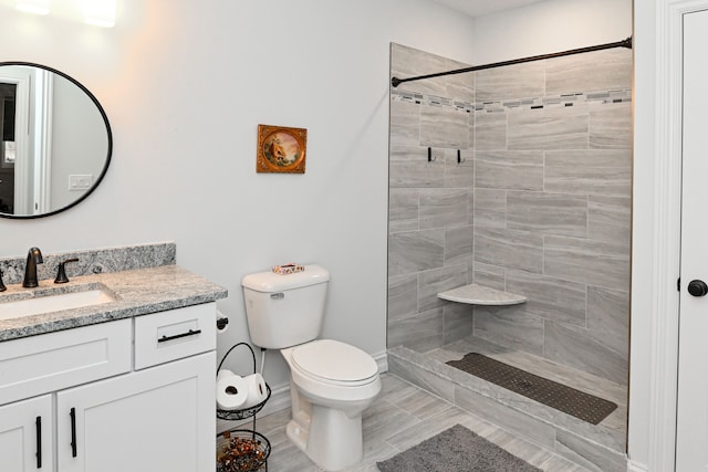 bathroom with tiled shower, vanity, and toilet