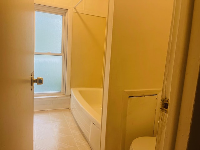 bathroom with toilet and a tub to relax in