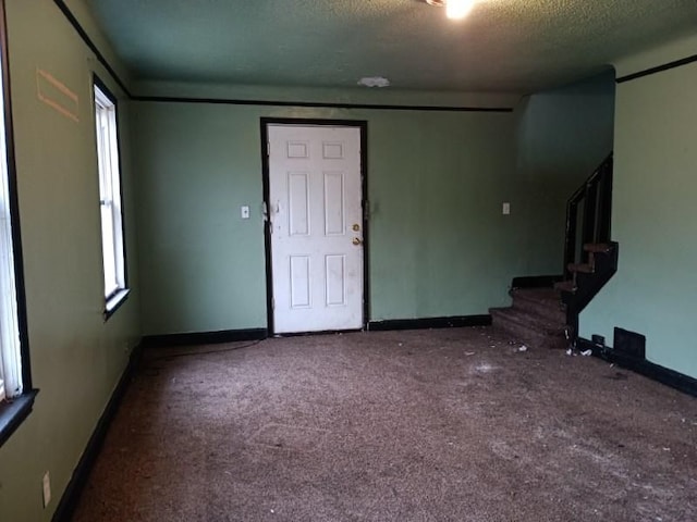 carpeted entryway with a textured ceiling