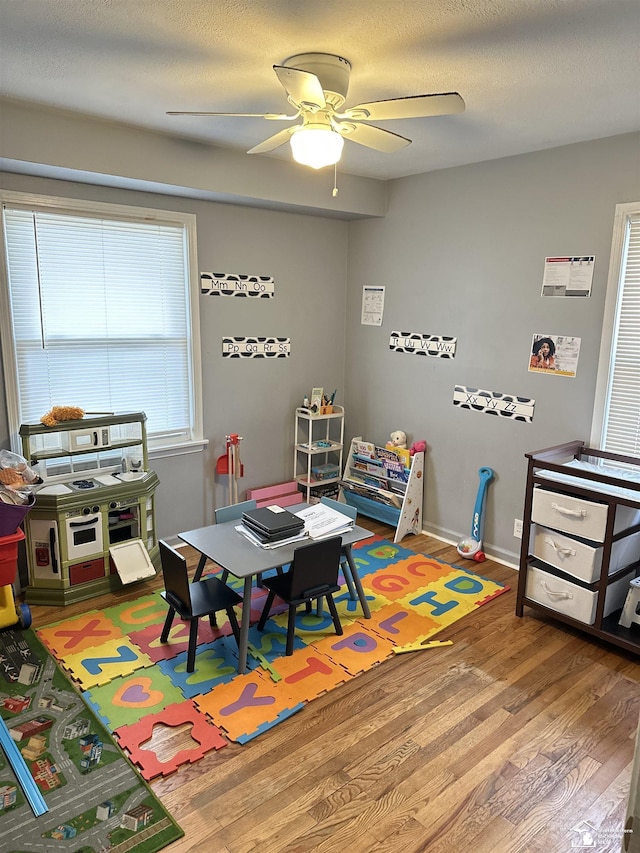 rec room with ceiling fan, wood-type flooring, and a textured ceiling