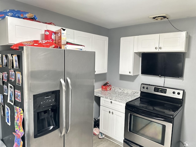 kitchen with white cabinets, stainless steel appliances, and light hardwood / wood-style flooring