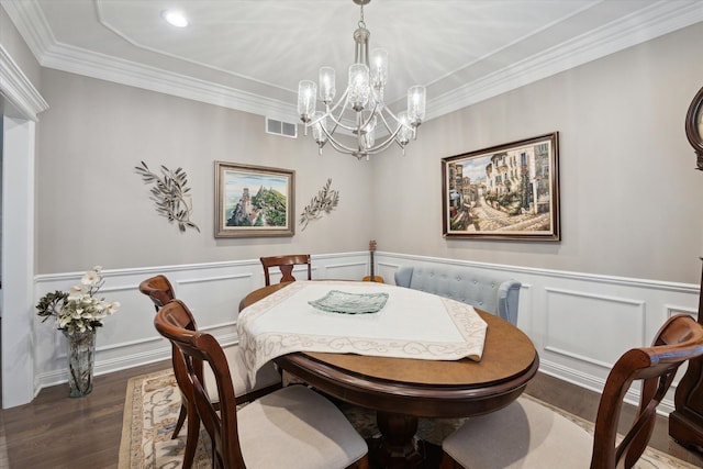 dining area with dark hardwood / wood-style flooring, crown molding, and an inviting chandelier