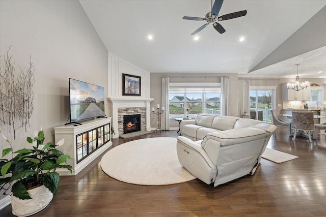 living room featuring dark hardwood / wood-style flooring, a fireplace, ceiling fan with notable chandelier, and lofted ceiling