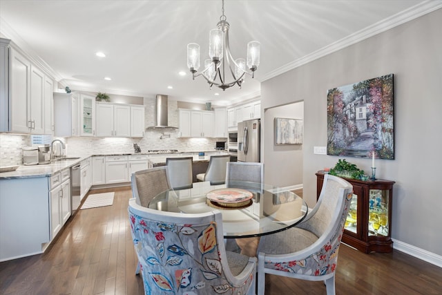 dining space featuring a notable chandelier, crown molding, sink, and dark wood-type flooring