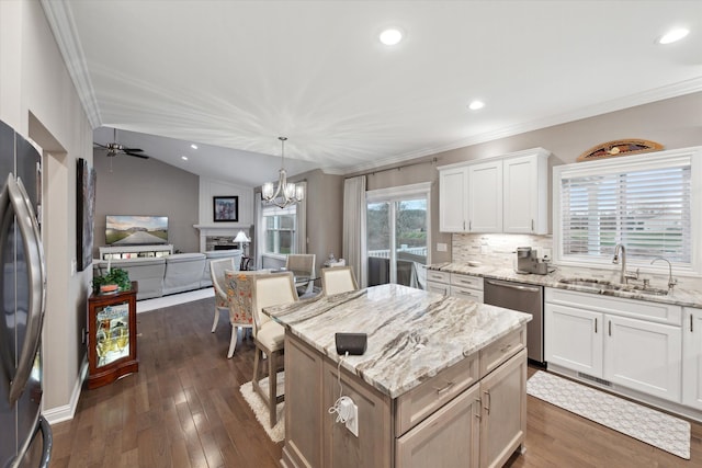 kitchen with stainless steel dishwasher, a kitchen island, sink, white cabinetry, and lofted ceiling