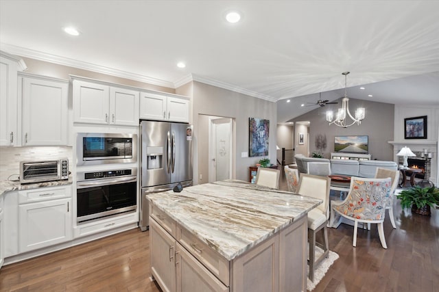 kitchen featuring light stone counters, a center island, white cabinets, and appliances with stainless steel finishes