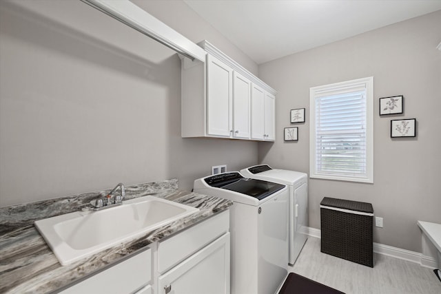 laundry room featuring washing machine and dryer, sink, and cabinets