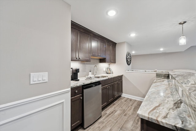 kitchen with dark brown cabinetry, sink, hanging light fixtures, light stone counters, and stainless steel dishwasher