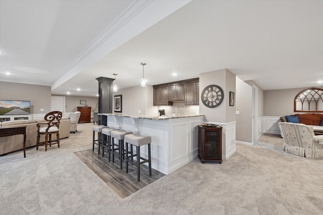 kitchen featuring decorative light fixtures, crown molding, light carpet, and tasteful backsplash