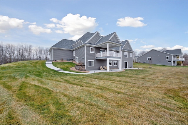 rear view of house featuring a yard, a balcony, and a patio area