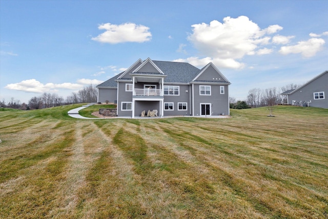 rear view of house featuring a balcony and a lawn