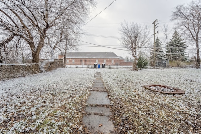 snow covered back of property with an outdoor fire pit