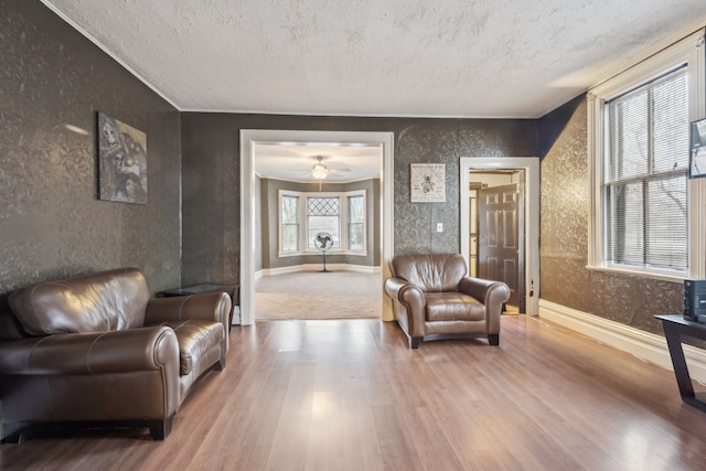 living area with ceiling fan, hardwood / wood-style floors, and a textured ceiling