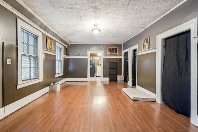 unfurnished room with hardwood / wood-style floors, a textured ceiling, a baseboard radiator, and ornamental molding