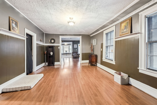 hall featuring crown molding, wood-type flooring, and a textured ceiling