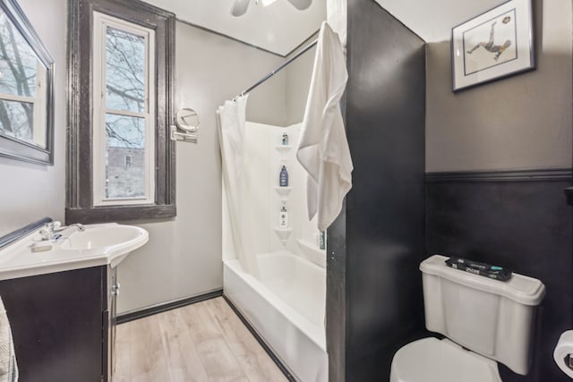 full bathroom featuring vanity, ceiling fan, wood-type flooring, shower / bathtub combination with curtain, and toilet