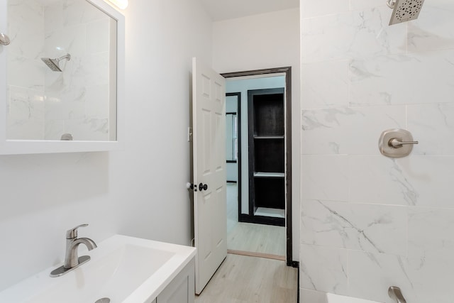 bathroom with tiled shower, wood-type flooring, and sink