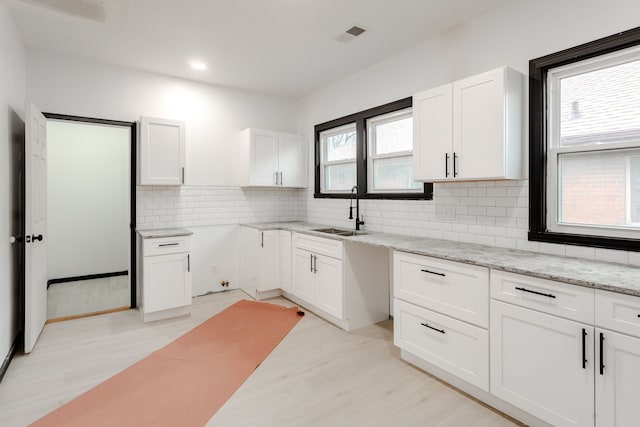 kitchen featuring white cabinets, backsplash, and sink