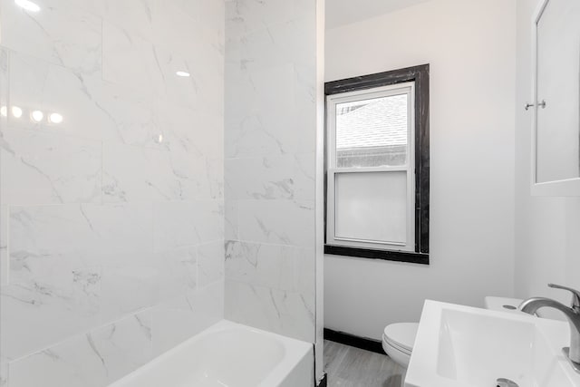 full bathroom with sink, tiled shower / bath, and toilet