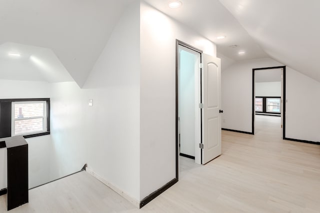 hallway with light hardwood / wood-style flooring and vaulted ceiling