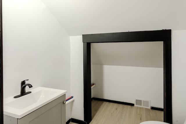 bathroom with hardwood / wood-style floors, vanity, and vaulted ceiling