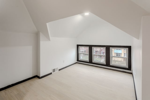 bonus room featuring light wood-type flooring and vaulted ceiling