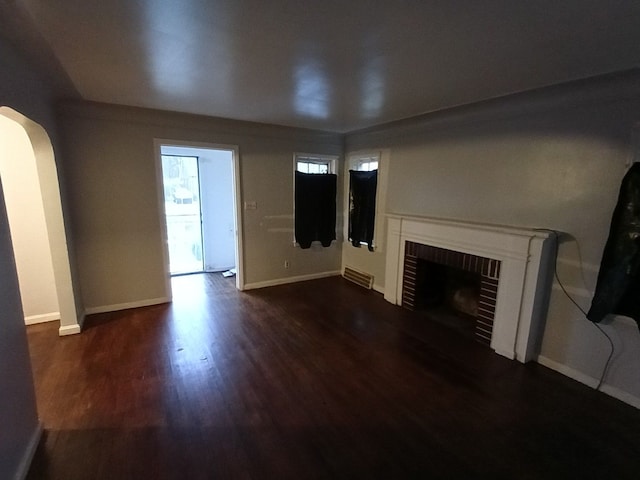 unfurnished living room with dark hardwood / wood-style floors and a brick fireplace