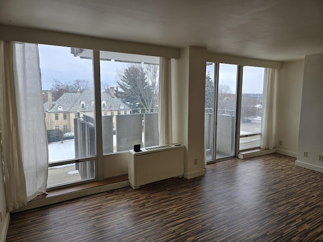 spare room featuring radiator heating unit and dark hardwood / wood-style flooring