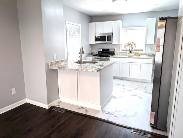 140 Stanley Ave, Jackson, MI 49203 - kitchen with appliances with stainless steel finishes, a sink, light stone countertops, white cabinetry, and baseboards