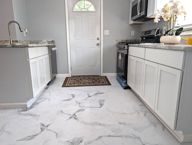 140 Stanley Ave, Jackson, MI 49203 - kitchen featuring stainless steel appliances, light marble finish floors, baseboards, and white cabinets