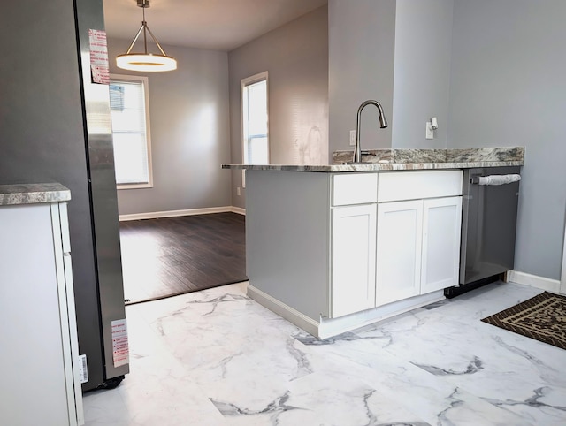 140 Stanley Ave, Jackson, MI 49203 - kitchen with light marble finish flooring, white cabinetry, baseboards, hanging light fixtures, and stainless steel appliances