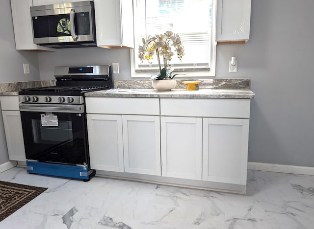 140 Stanley Ave, Jackson, MI 49203 - kitchen featuring appliances with stainless steel finishes, light marble finish floors, white cabinets, and baseboards