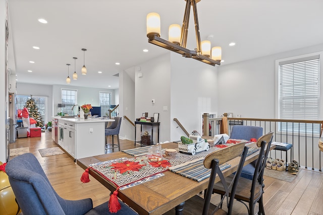 dining space with an inviting chandelier, sink, and light hardwood / wood-style flooring