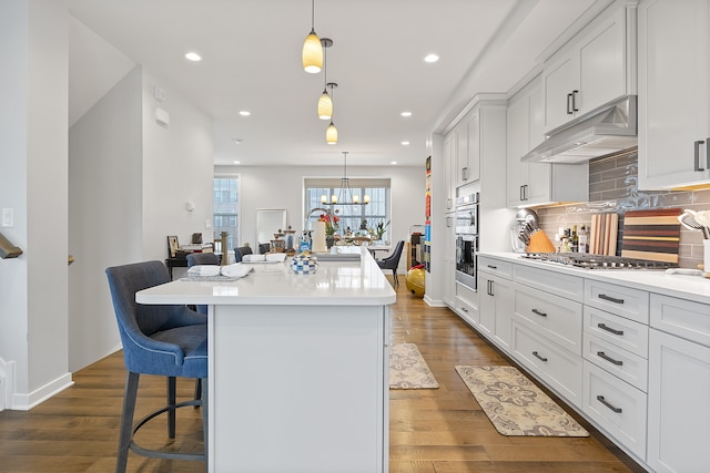 kitchen featuring a kitchen island with sink, white cabinetry, pendant lighting, and a kitchen breakfast bar