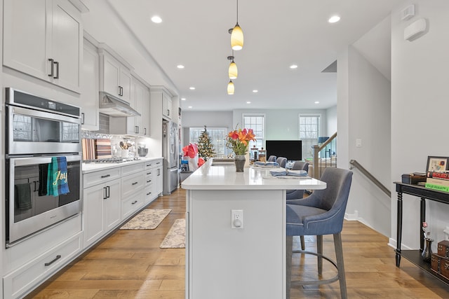 kitchen with pendant lighting, a breakfast bar area, white cabinets, a center island, and stainless steel appliances