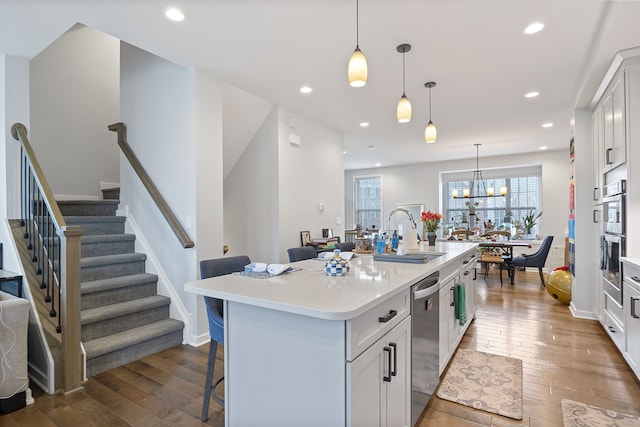 kitchen with pendant lighting, sink, white cabinets, a kitchen breakfast bar, and a kitchen island with sink